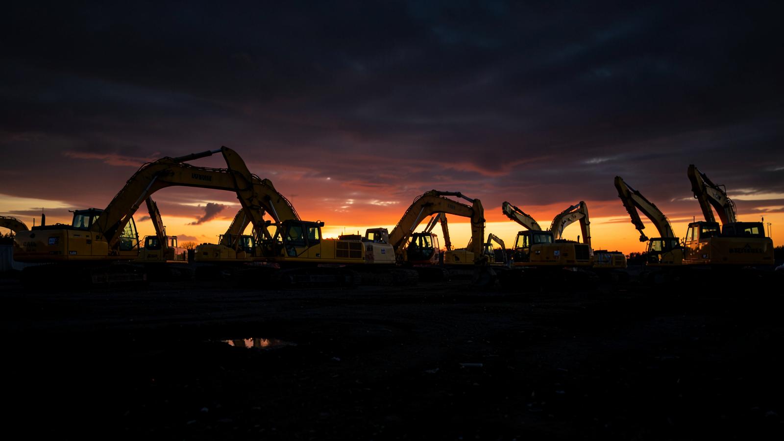 Excavators lined up at sunset